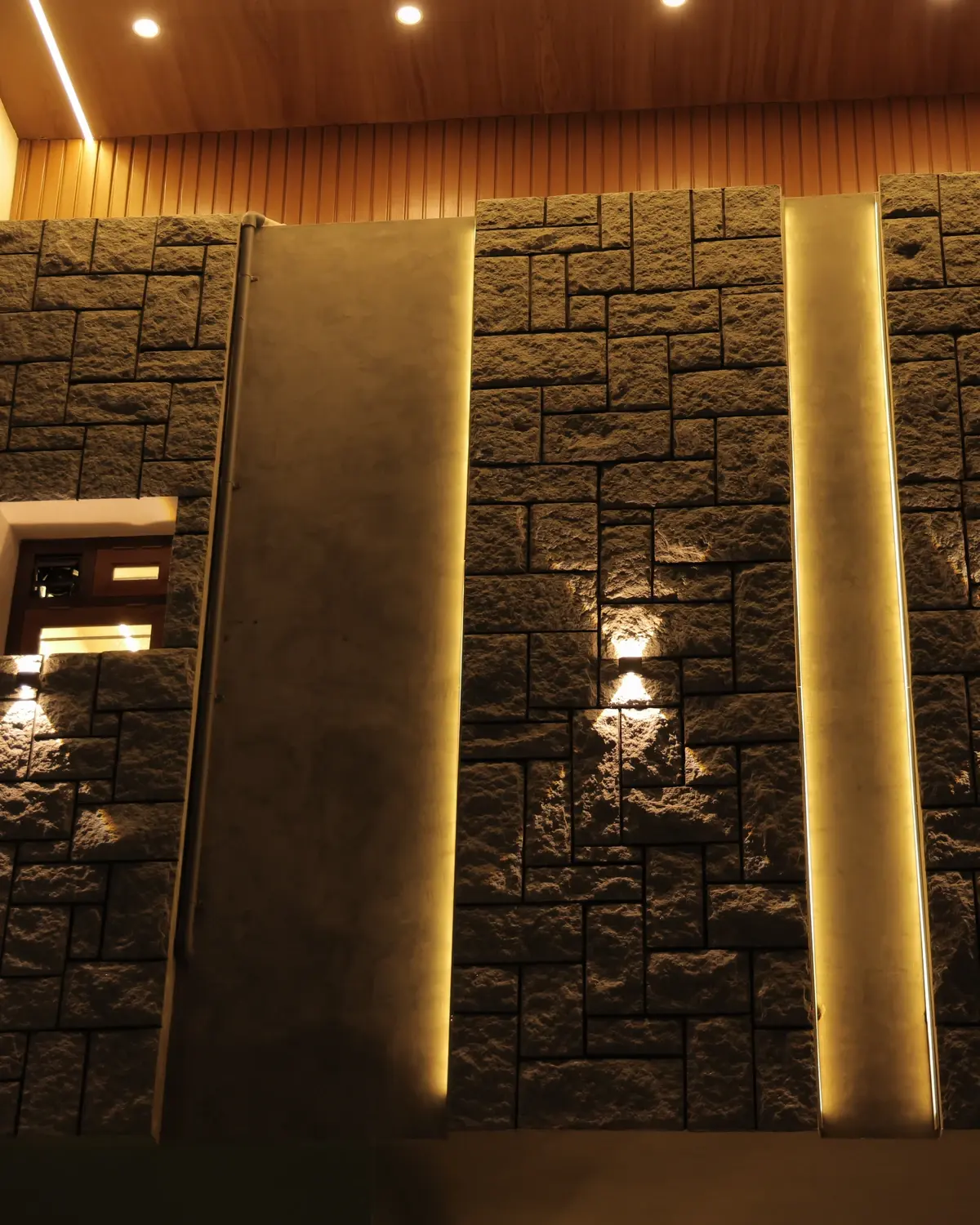 Split-face natural stone wall masonry and architectural lighting — Sunil Residence